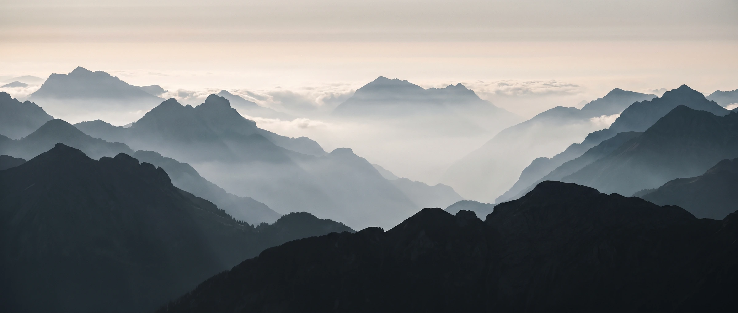 Gestaffelte Bergkämme über einem Nebelmeer, kühles Morgenlicht