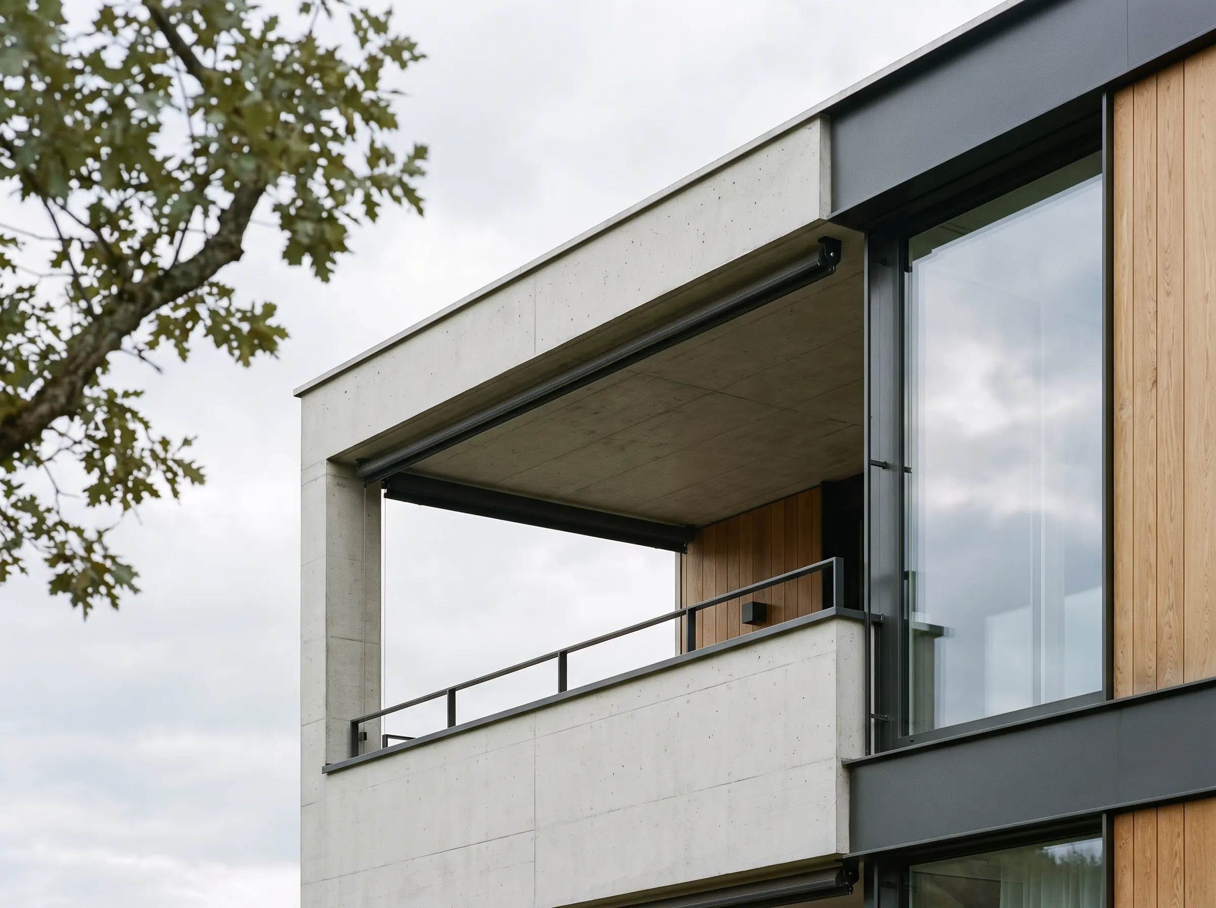 Obergeschoss eines Neubaus aus Sichtbeton und Holz, Loggia vor hellem Himmel
