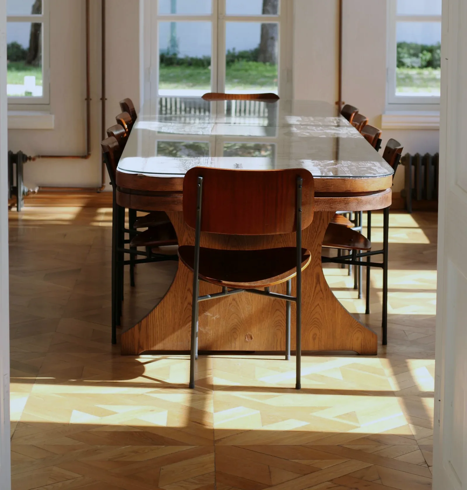 Historischer Raum mit Sonnenlicht auf dem Parkett und einem Tisch am Fenster