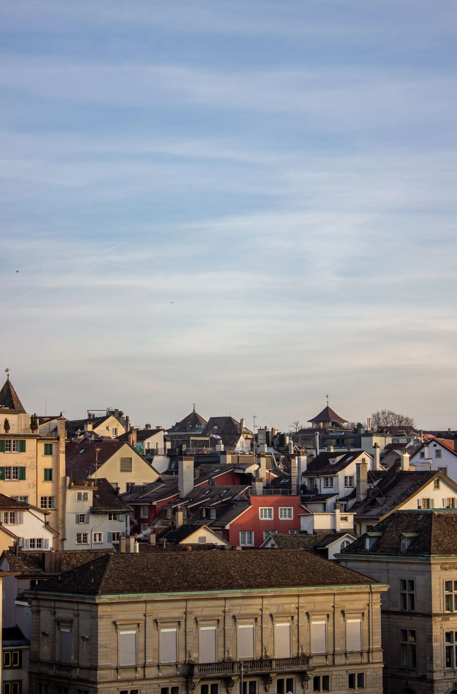 Zürcher Altstadtdächer im Abendlicht unter weitem Himmel